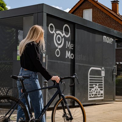 Frau mit Fahrrad vor einer Fahrradabstellanlage der Mobilstation