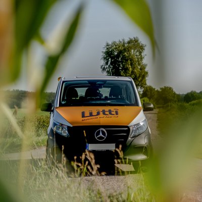 On-Demand-Verkehr Luetti Fahrzeug hinter Graesern