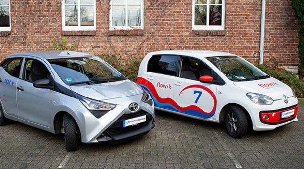 Zwei Autos – stadt>k und flow>k – parkend vor einem Haus