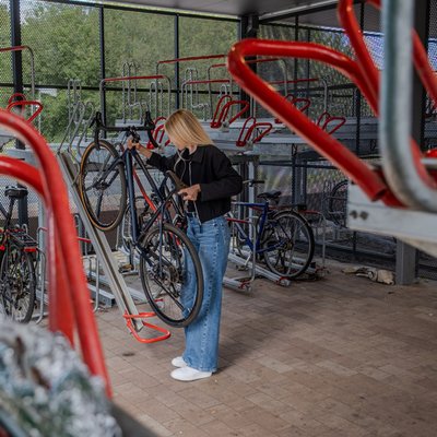 Frau stellt ihr Fahrrad in die obere Etage einer doppelstoeckigen Fahrradanlage