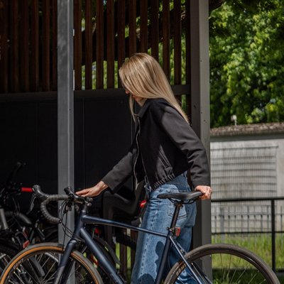 Frau schiebt ihr Fahrrad in einen Fahrradabstellplatz der radbar